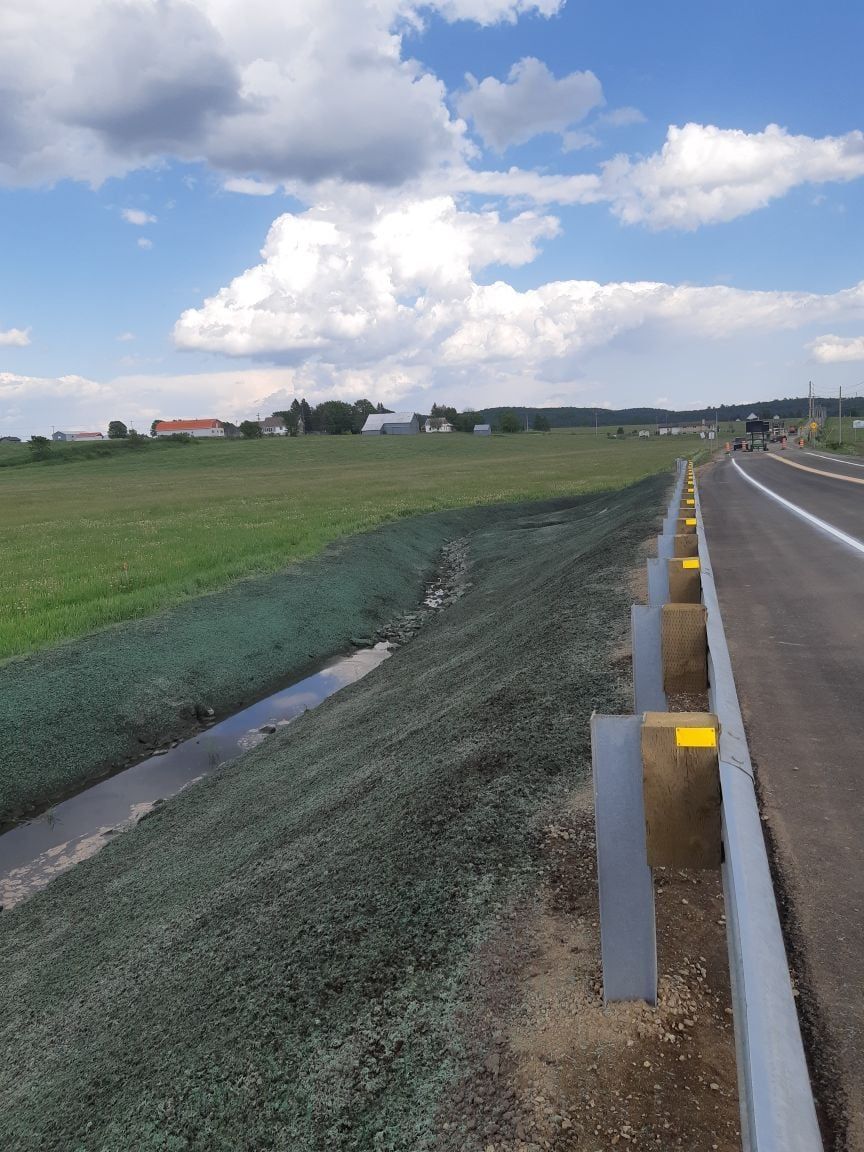 Une route traversant un champ herbeux traversé par un ruisseau.