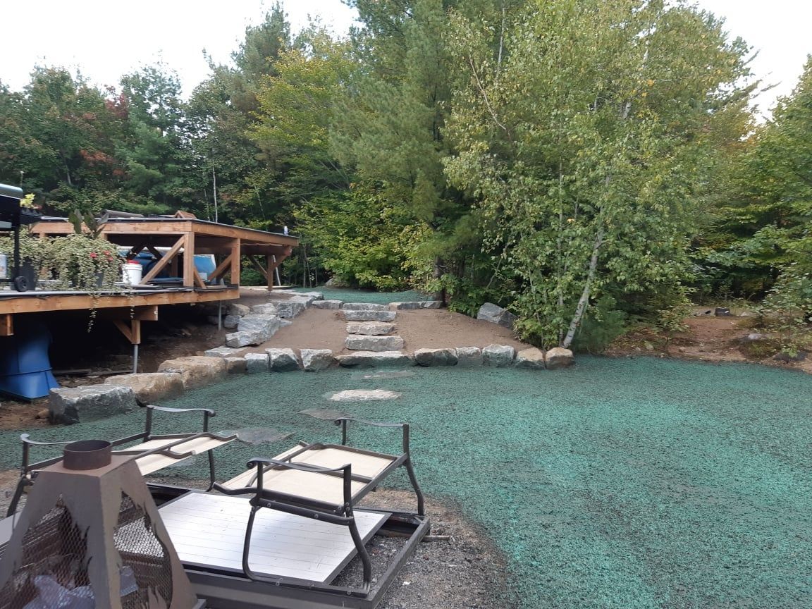 Une pelouse verte luxuriante avec une terrasse en bois en arrière-plan.