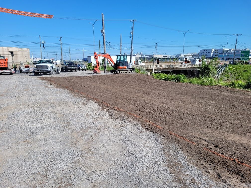 Un chantier avec beaucoup de terre et des camions garés sur le bord de la route.