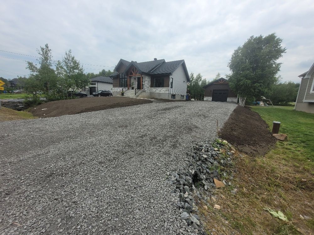 Une allée de gravier menant à une maison avec un garage.