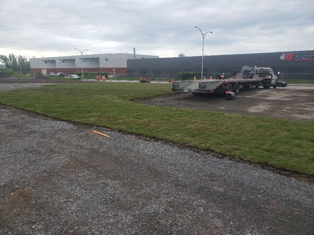 Une dépanneuse est garée dans un champ herbeux devant un bâtiment.