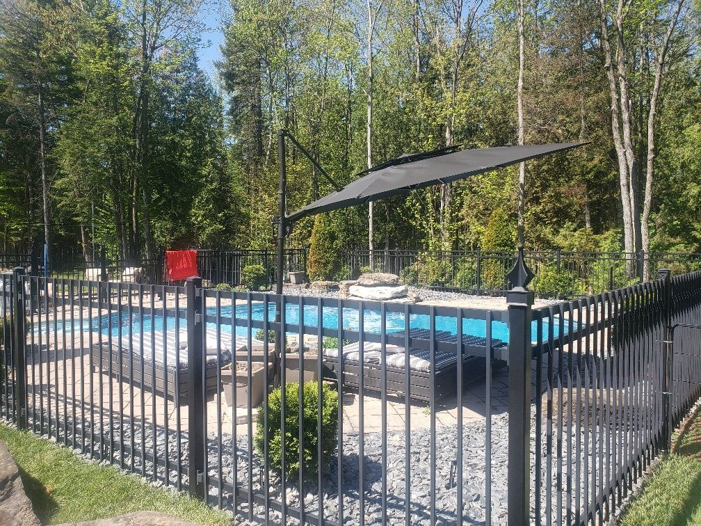 Une clôture noire entoure une grande piscine.