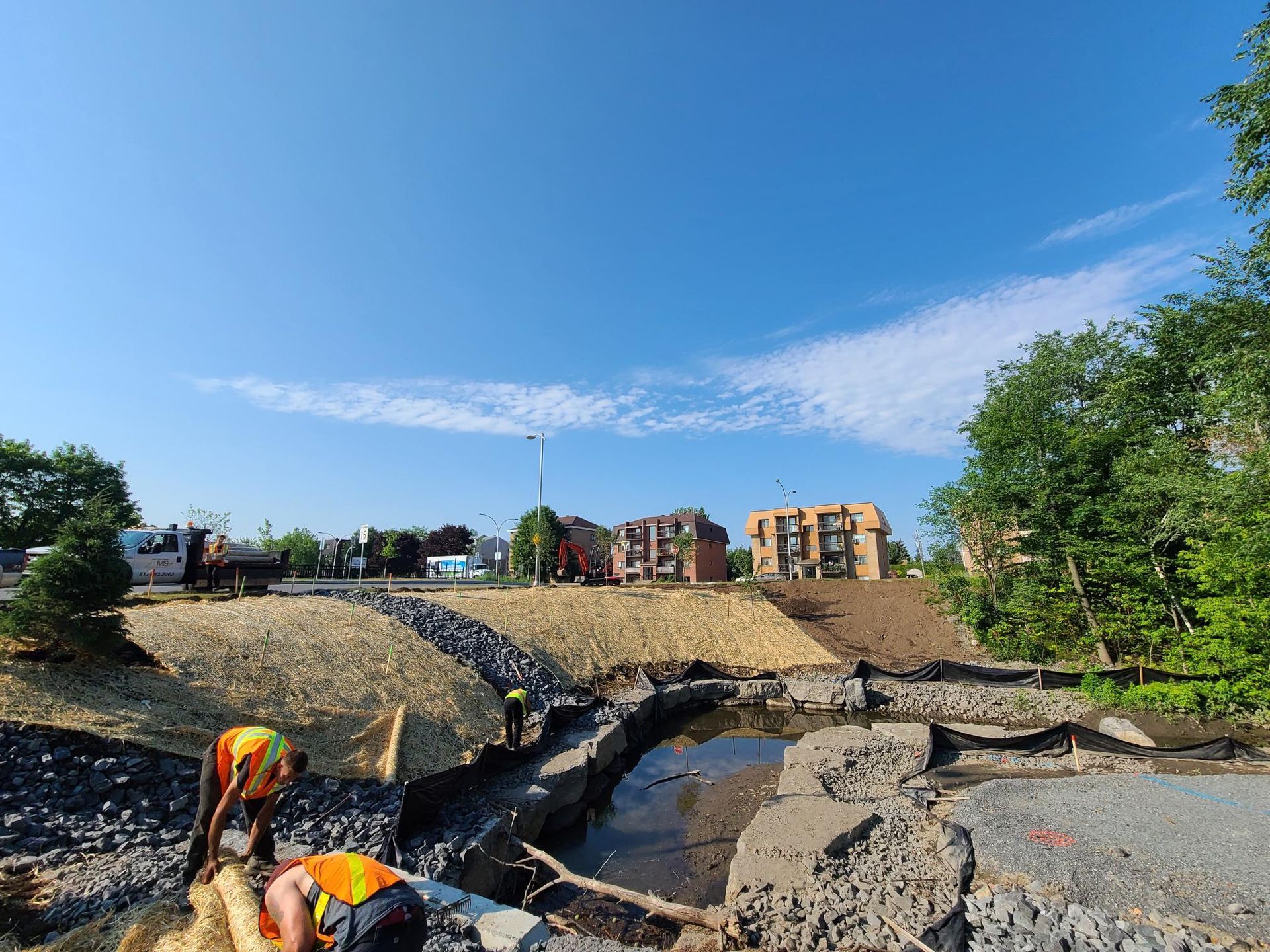 Un groupe de personnes travaille sur un chantier de construction à côté d'une rivière.