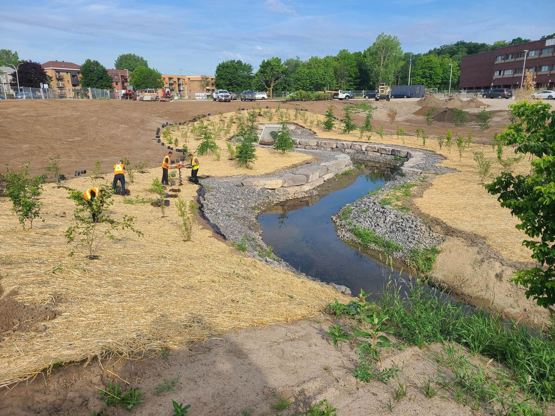 Un petit ruisseau qui traverse un champ avec un bâtiment en arrière-plan.