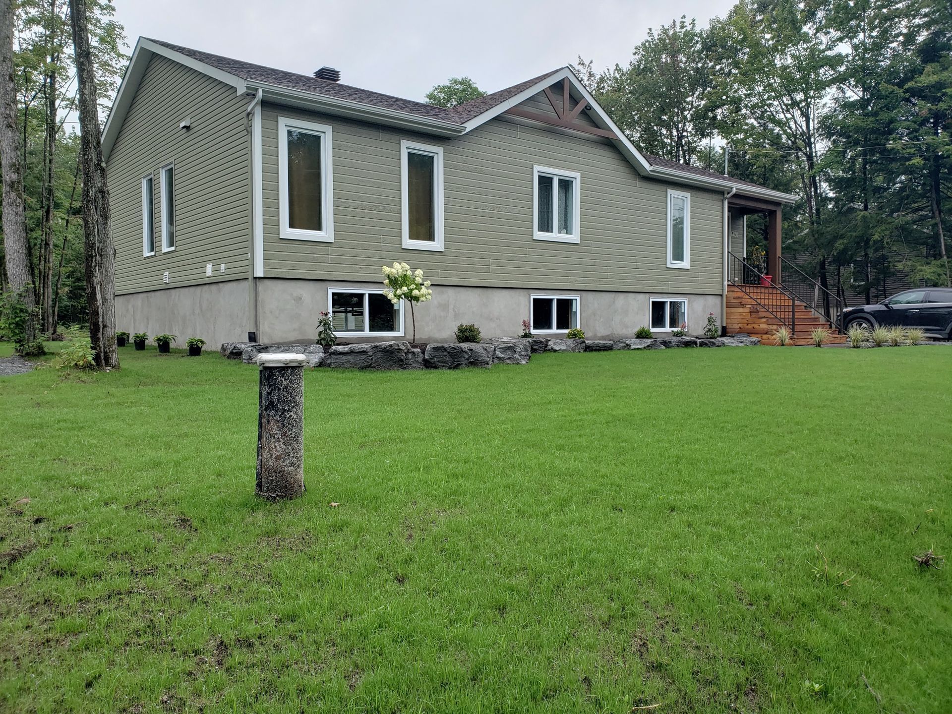 Une grande maison avec beaucoup de fenêtres se trouve au milieu d'un champ vert luxuriant.