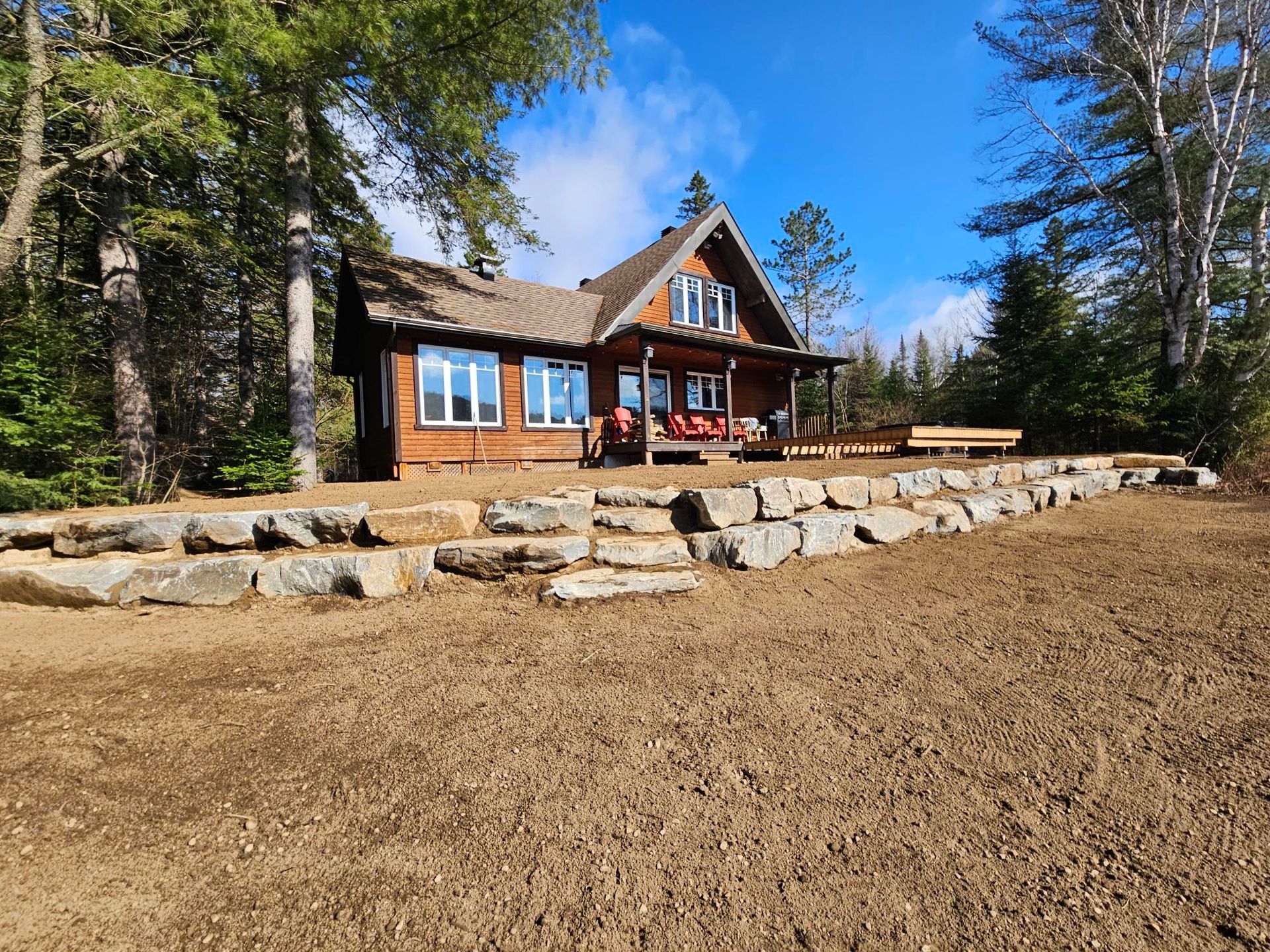 Une petite maison est assise au sommet d'une colline de terre entourée d'arbres.