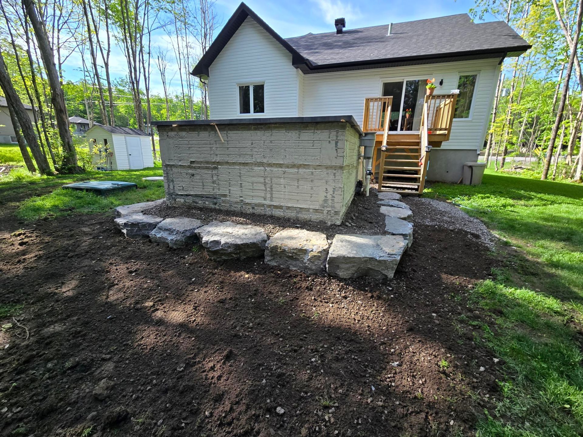 Une maison blanche avec une terrasse en bois et des escaliers dans l'arrière-cour.