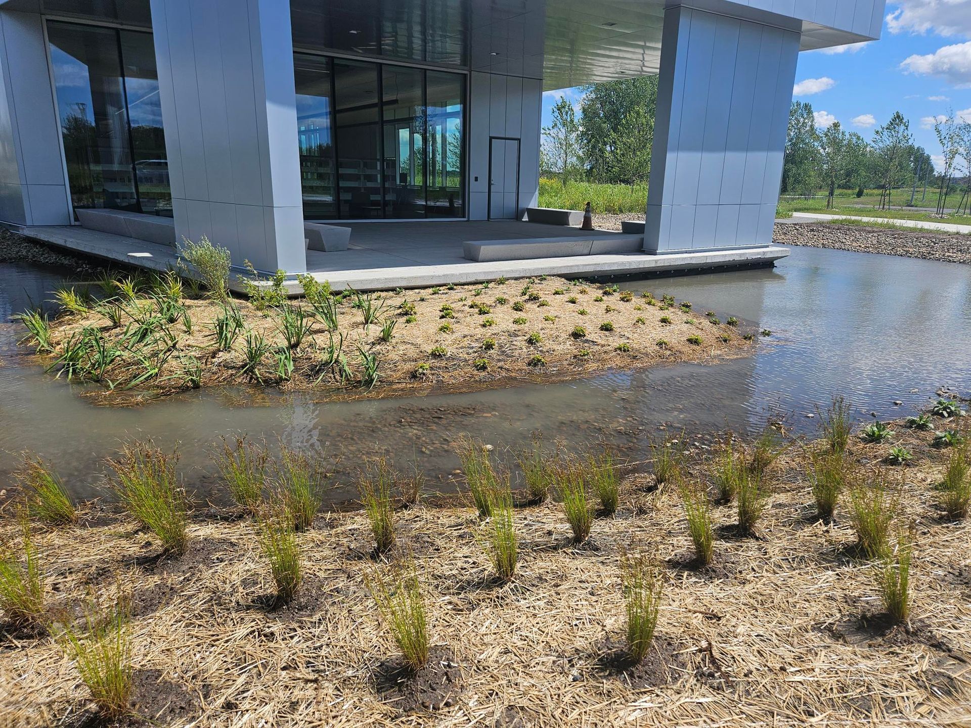Un bâtiment avec beaucoup de fenêtres et un étang devant.