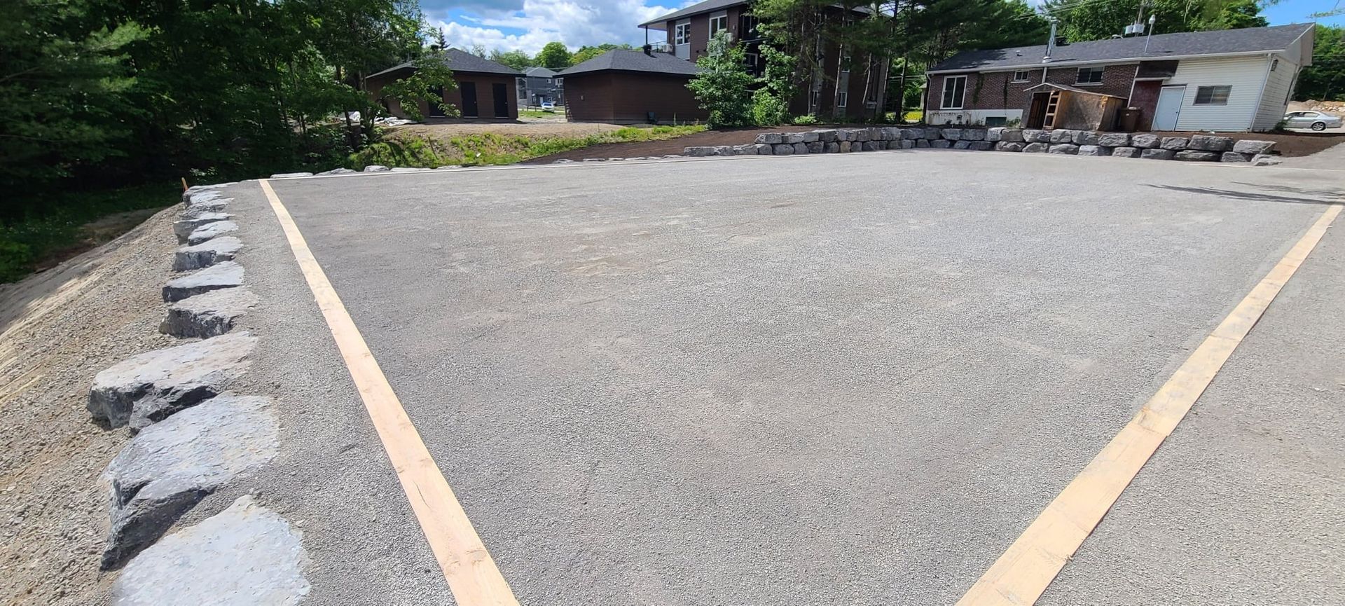 Un parking avec une ligne blanche sur le côté et une maison en arrière-plan.