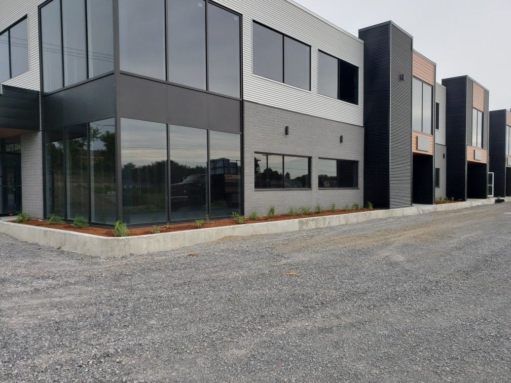 Un grand bâtiment avec beaucoup de fenêtres et une allée de gravier devant lui