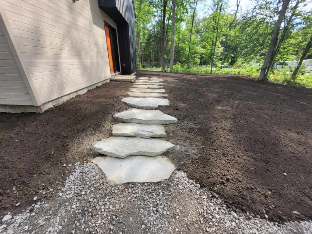 Un chemin de pierre menant à une maison dans les bois.