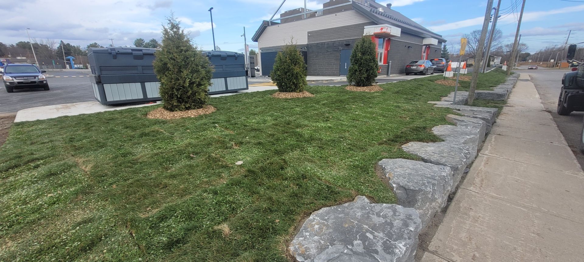 Un trottoir menant à un bâtiment avec beaucoup d'herbe et de rochers.