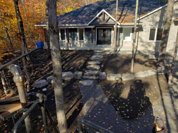 Une vue aérienne d'une maison avec une passerelle menant à elle entourée d'arbres.