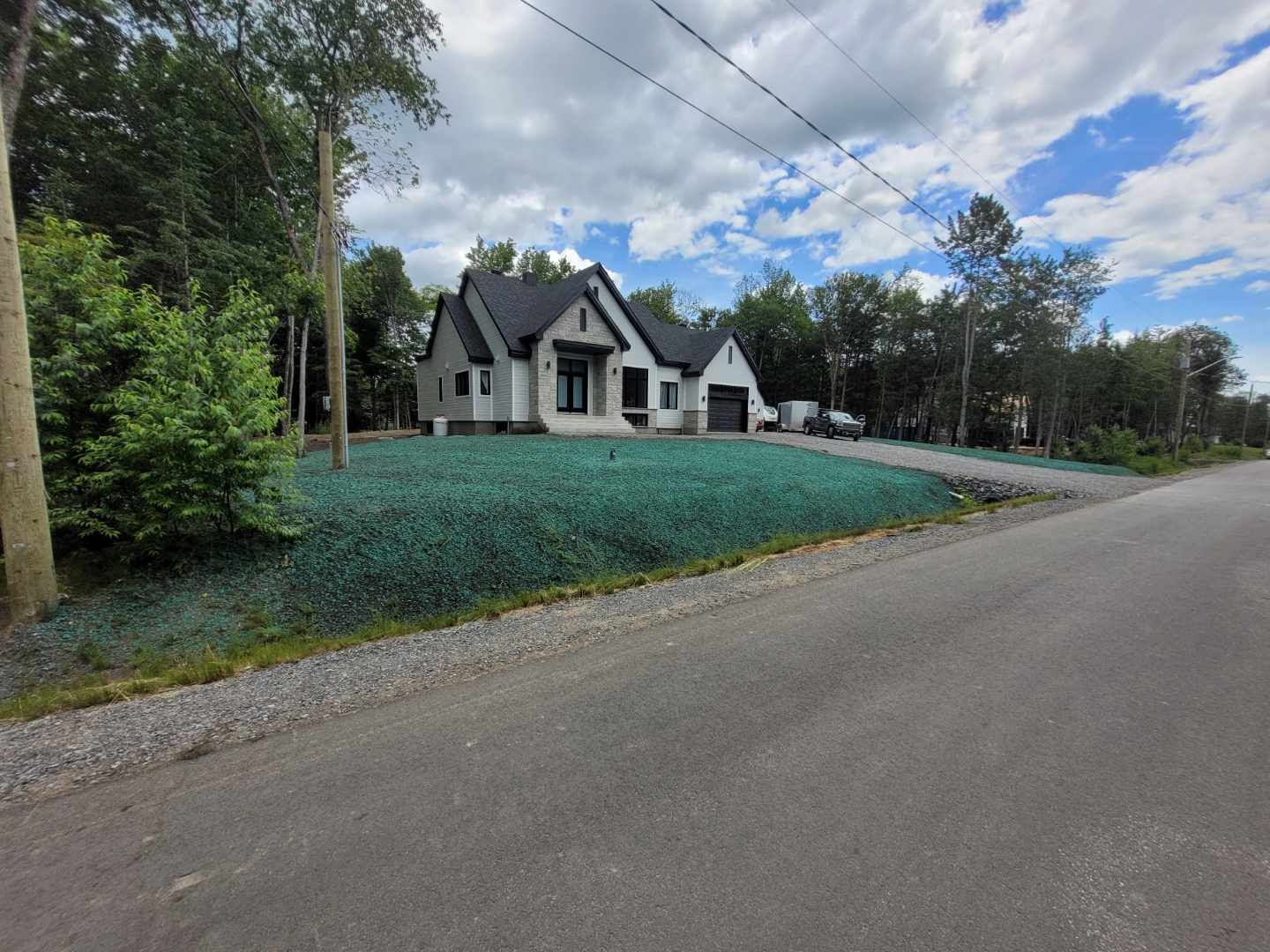 Une maison est située sur le bord d'une route à côté d'un champ herbeux.