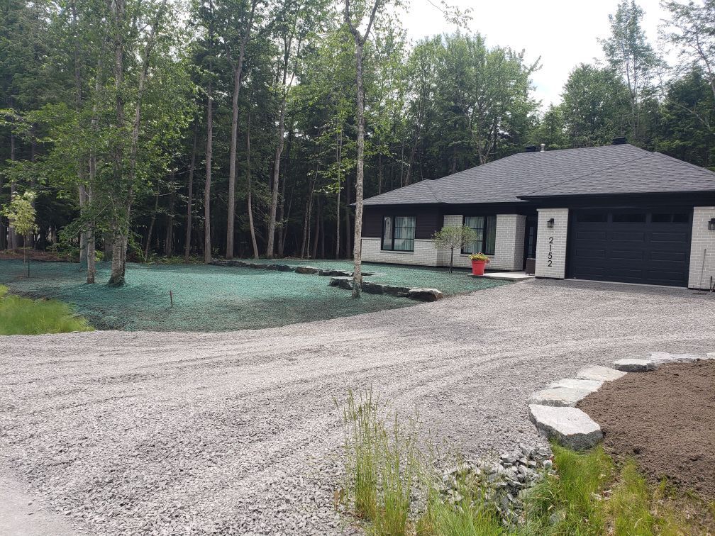 Une maison avec une allée de gravier qui y mène est entourée d'arbres.