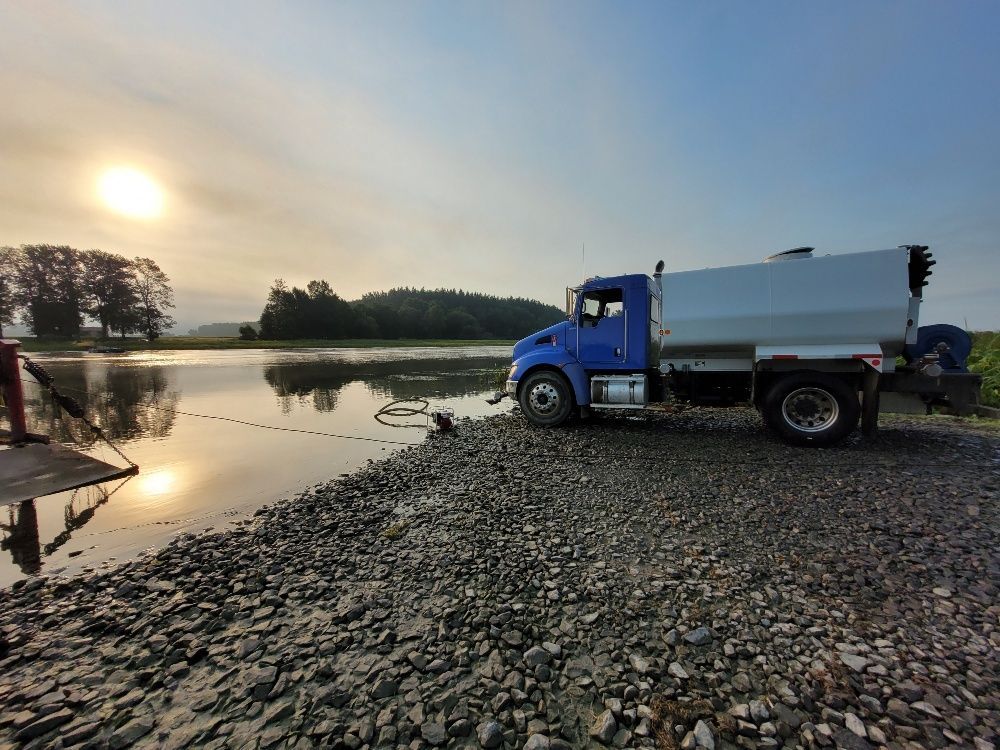 Un camion bleu est garé à côté d'un plan d'eau.