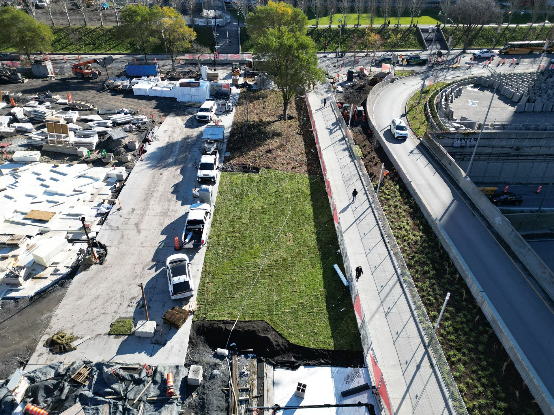 Une vue aérienne d'un chantier de construction avec une grande zone herbeuse au milieu.