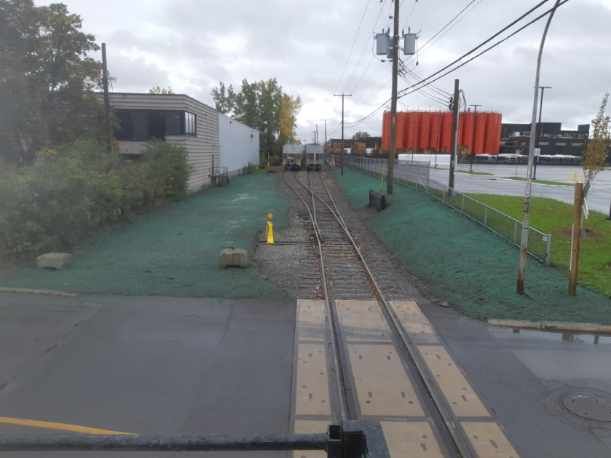 Un train descend les voies à côté d'une zone herbeuse.