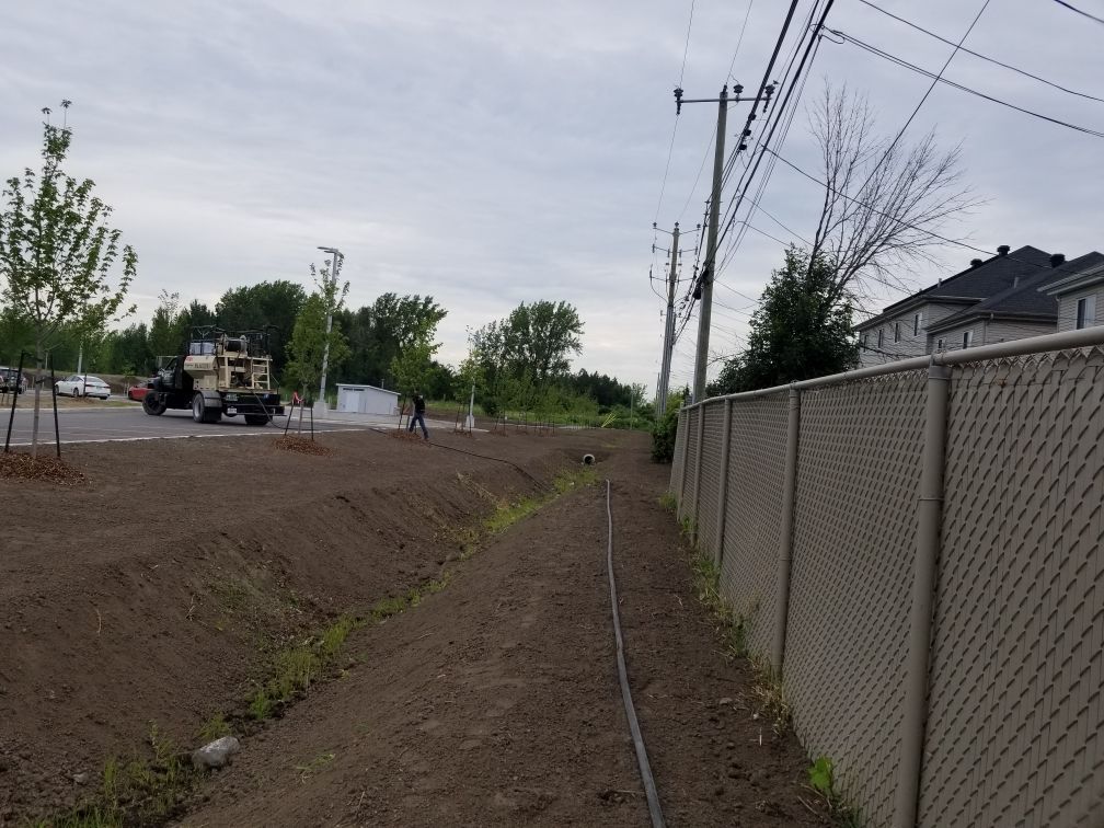 Une clôture grillagée le long d'un chemin de terre