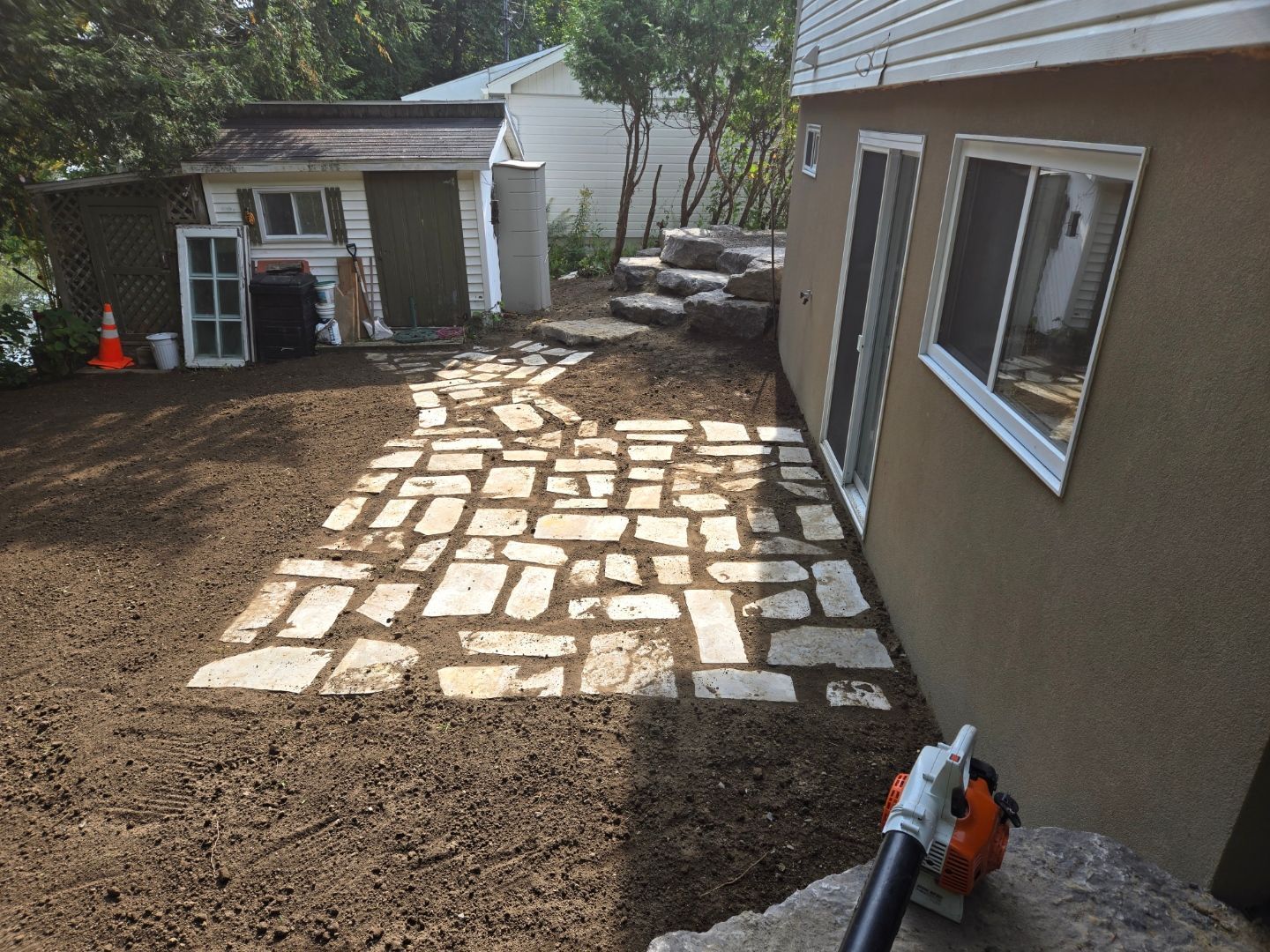 Une allée en pierre est en cours de construction devant une maison.