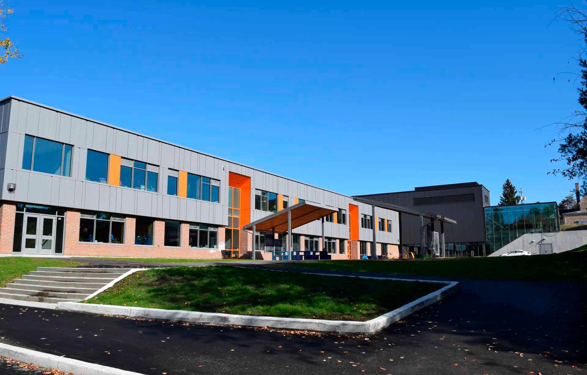 Un grand bâtiment avec beaucoup de fenêtres est entouré d'herbe et d'arbres.