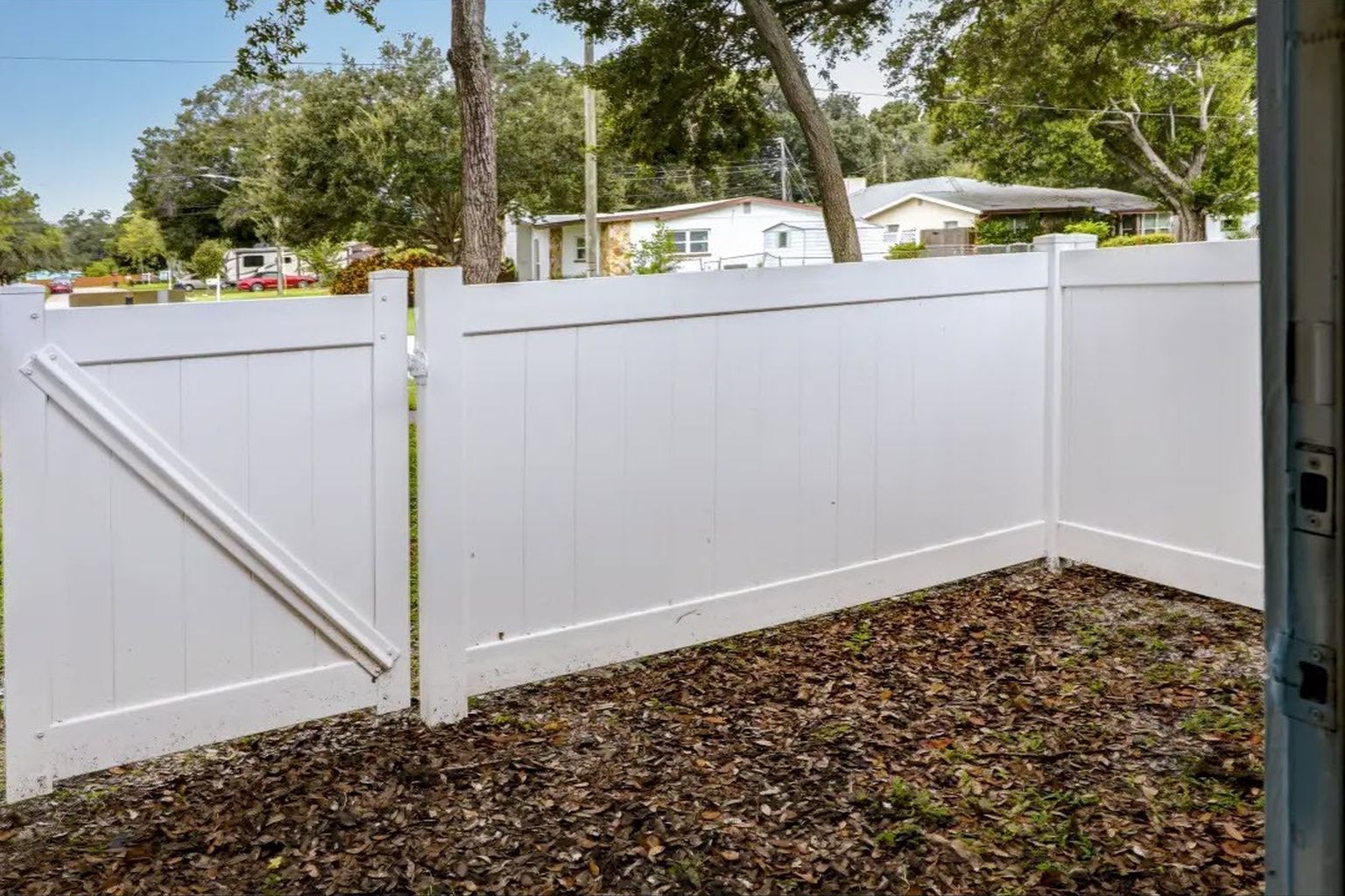 White vinyl fence with gate in a yard.