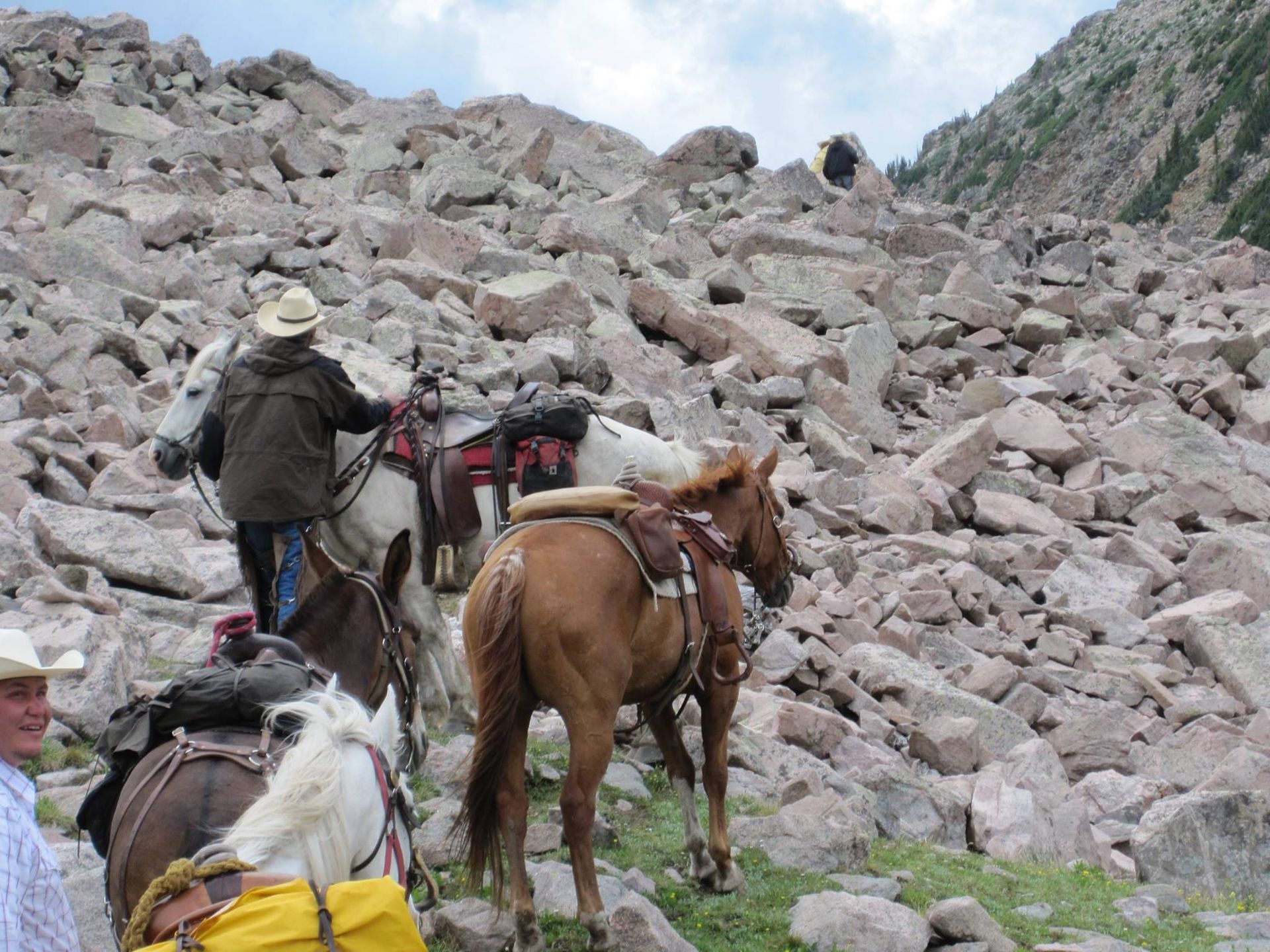 A group of people riding horses on a rocky hillside
