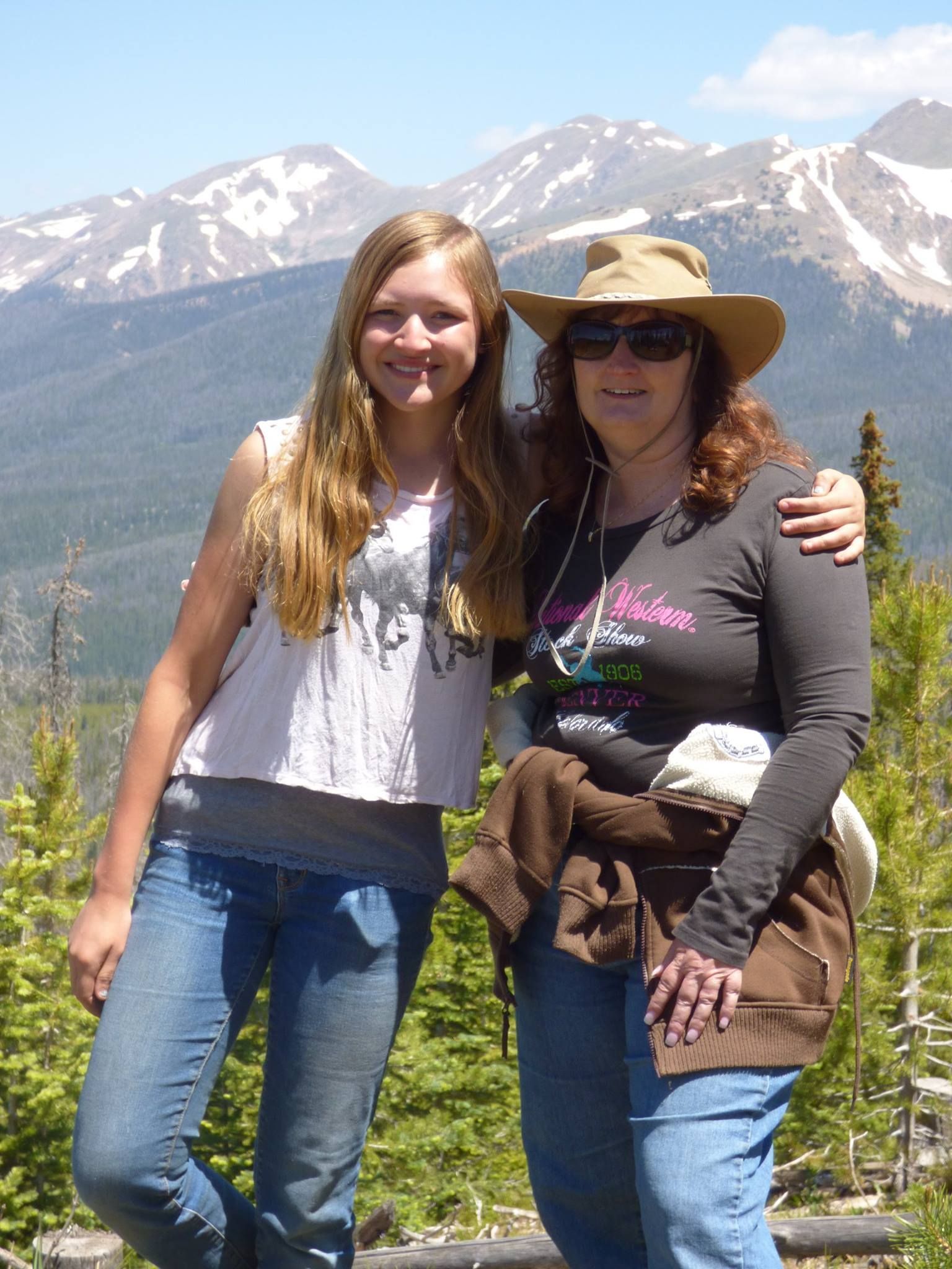Two women posing for a picture with mountains in the background