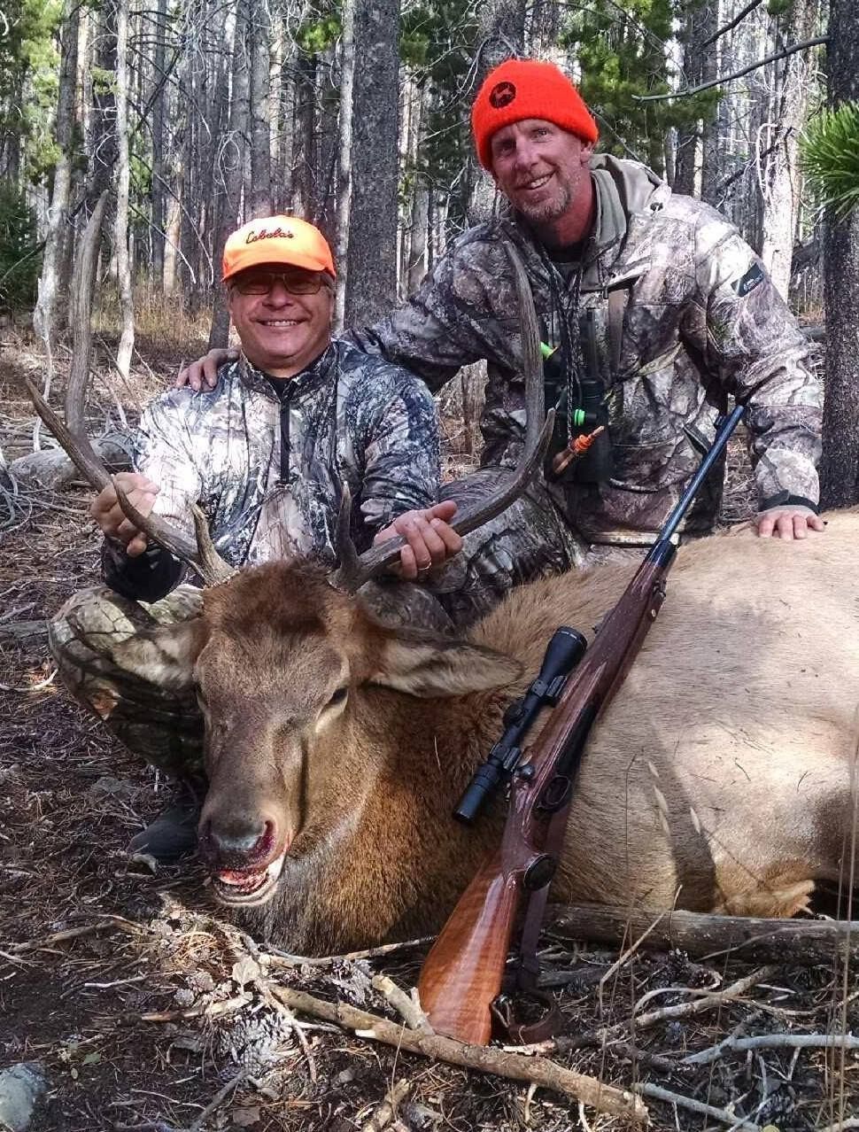 A hunter smiling next to his buck