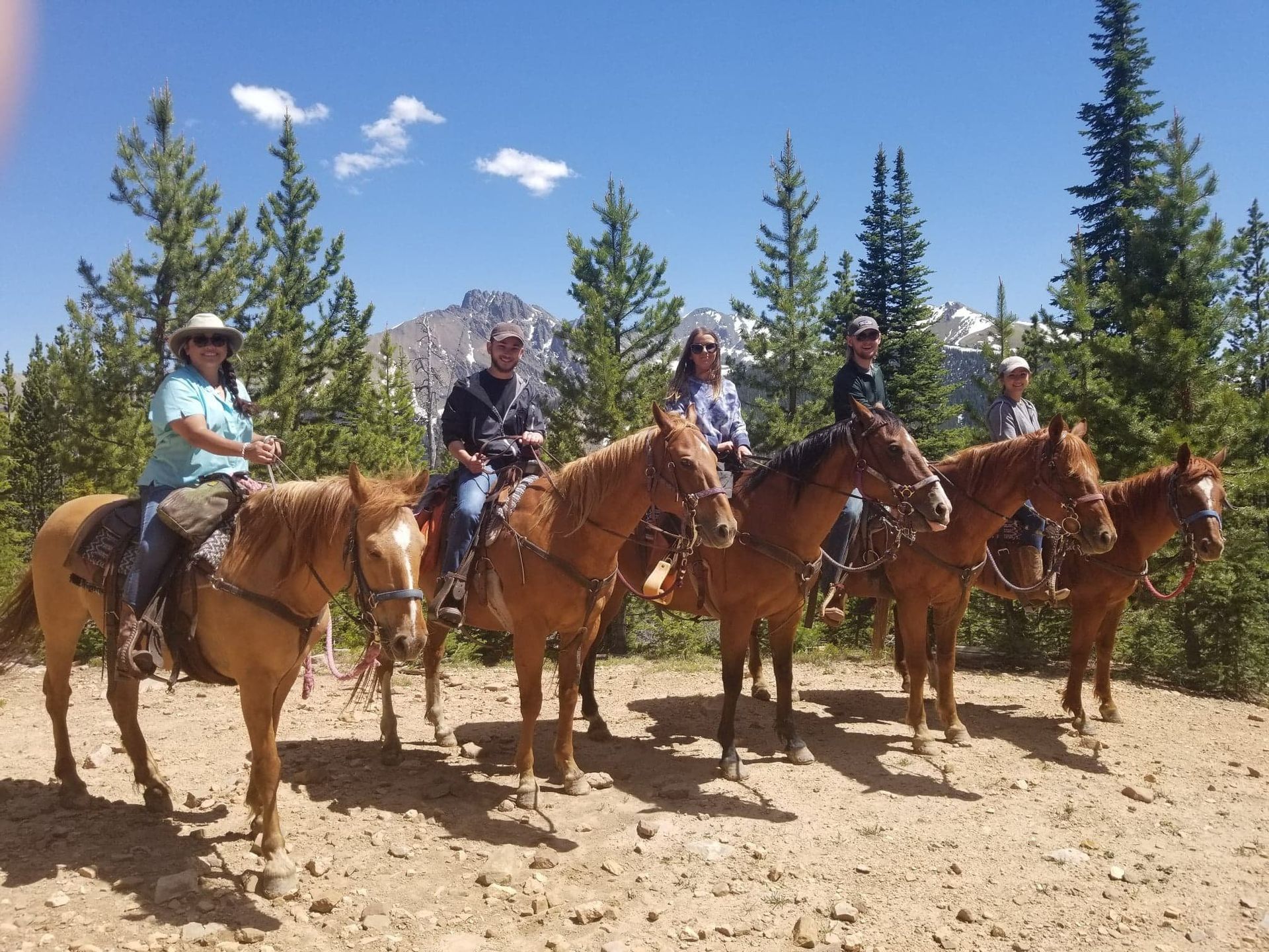 A group of people riding horses on a dirt road