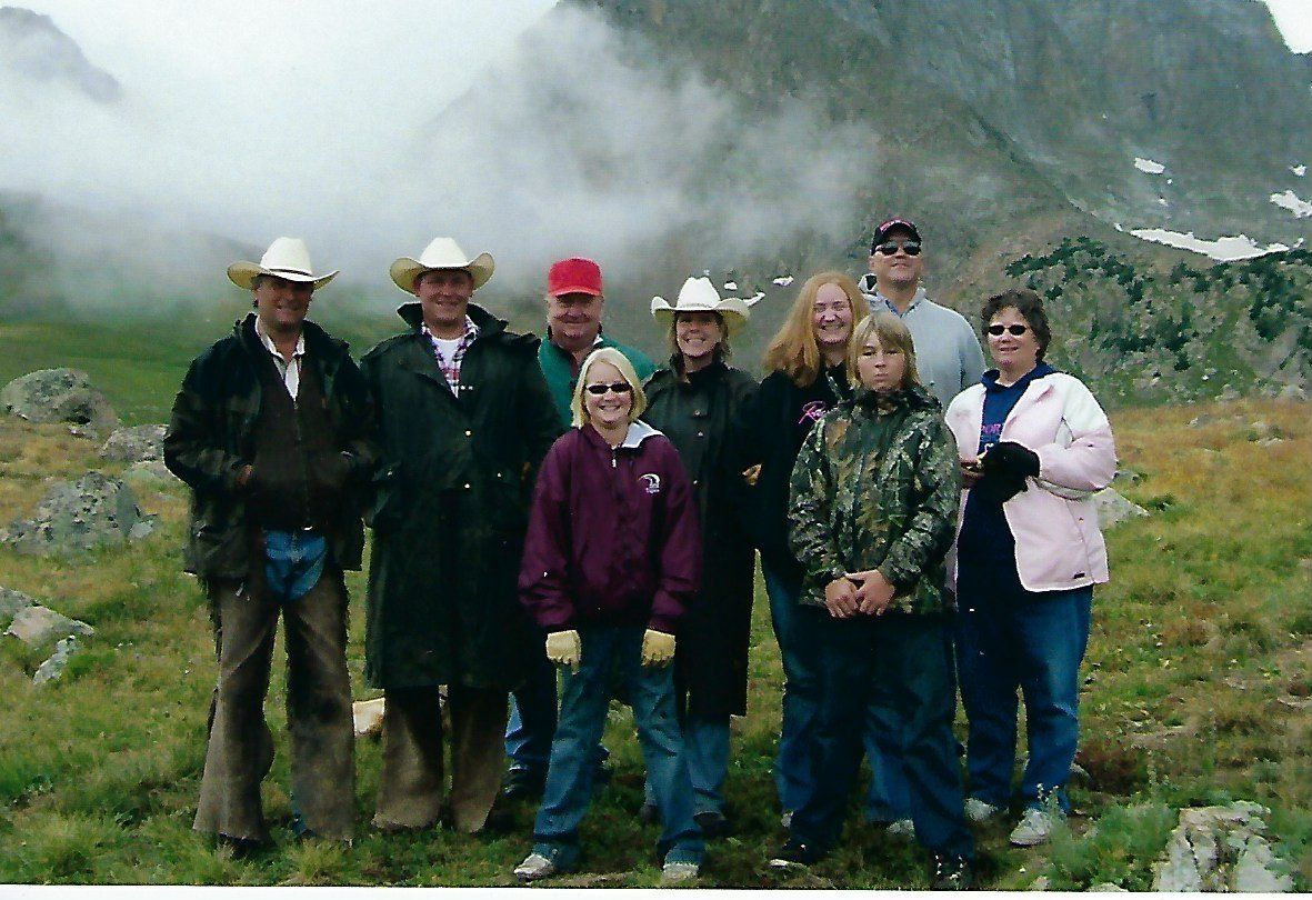 A group of people standing in a field with mountains in the background