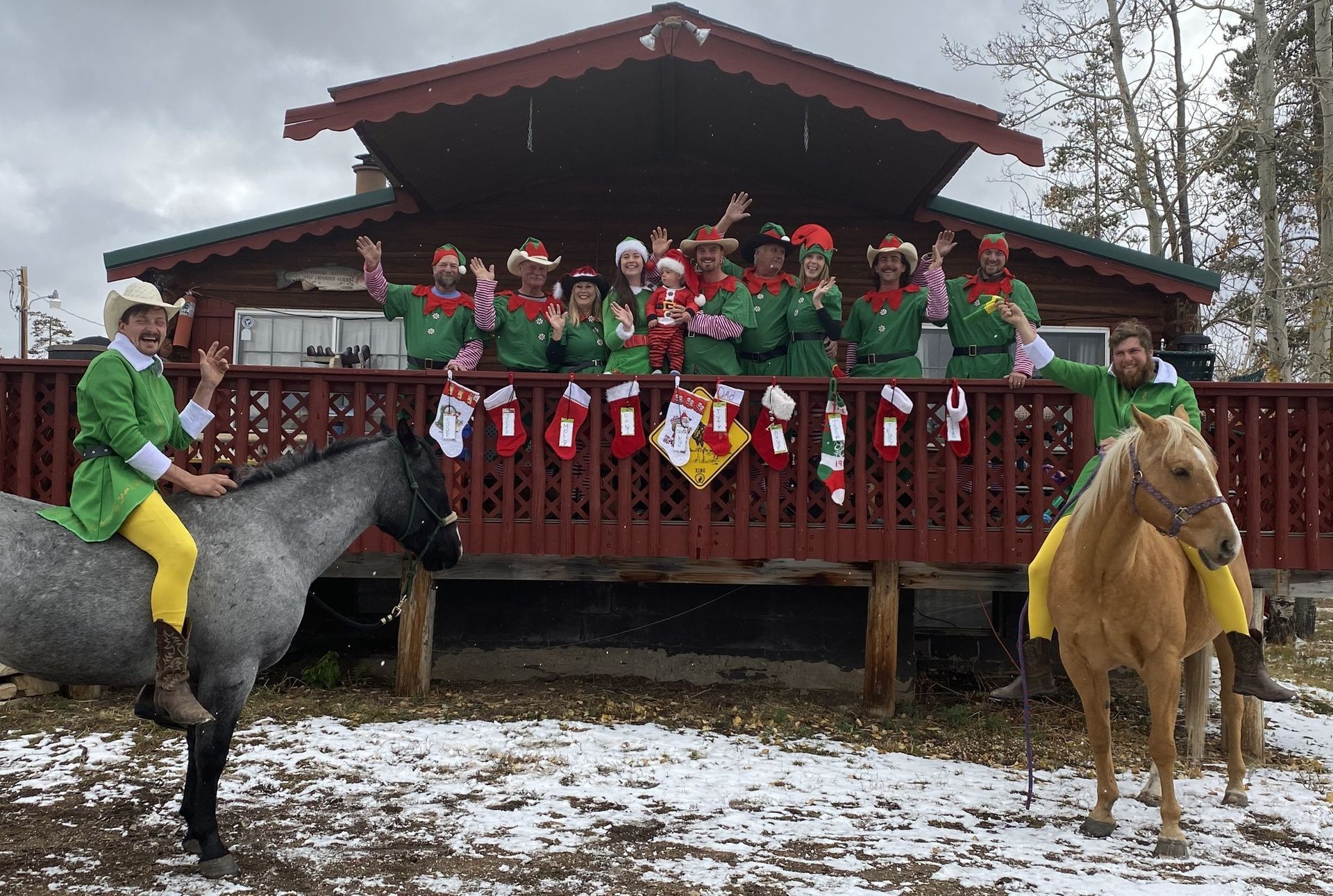 A group of people dressed as elves are riding horses in front of a house.
