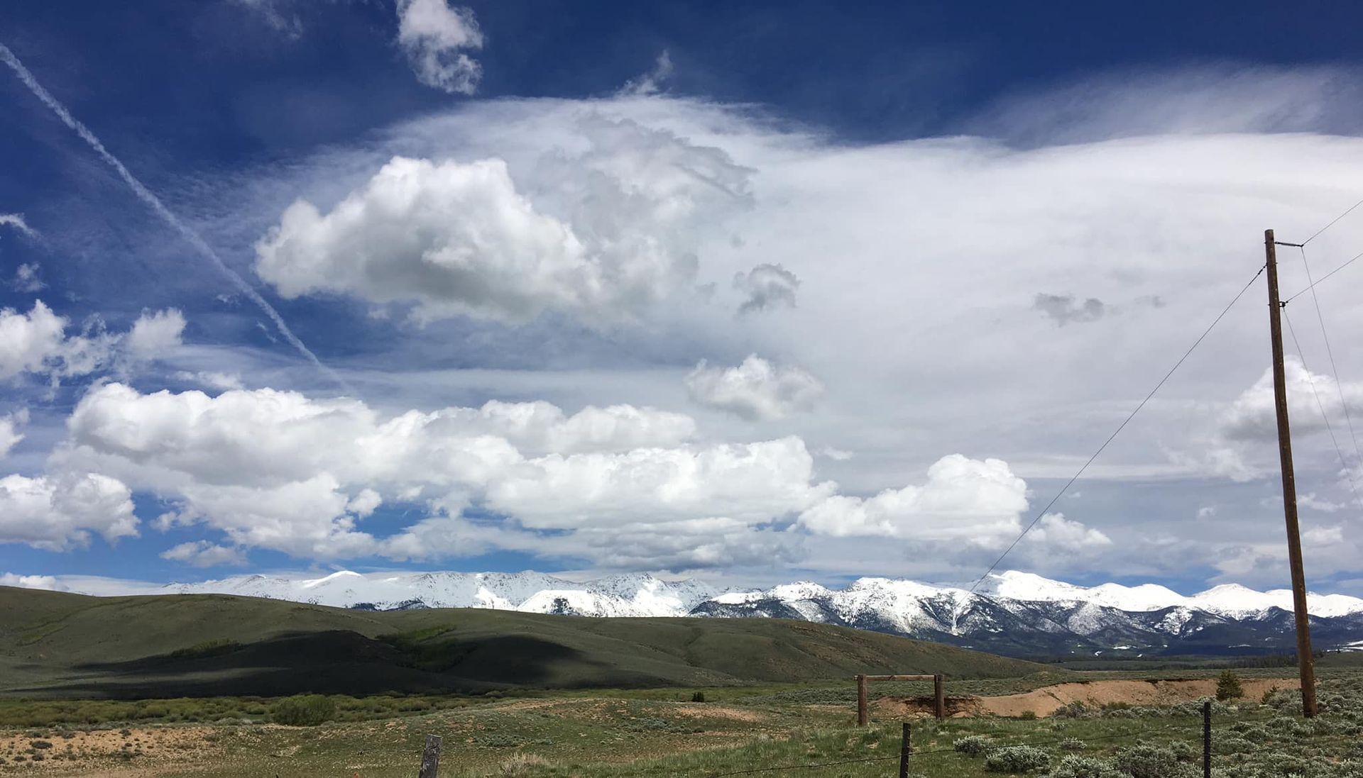 A cloudy sky over a mountain range with a telephone pole in the foreground.