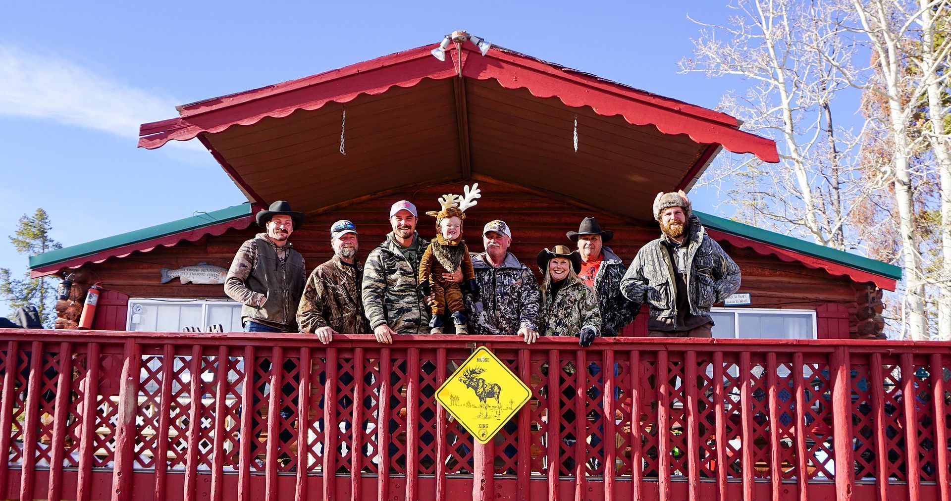 A group of people are standing on a deck in front of a cabin.