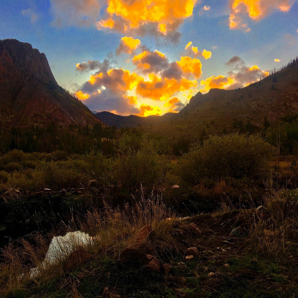A sunset over a valley with mountains in the background