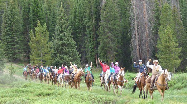 A large group of people are riding horses in a field.
