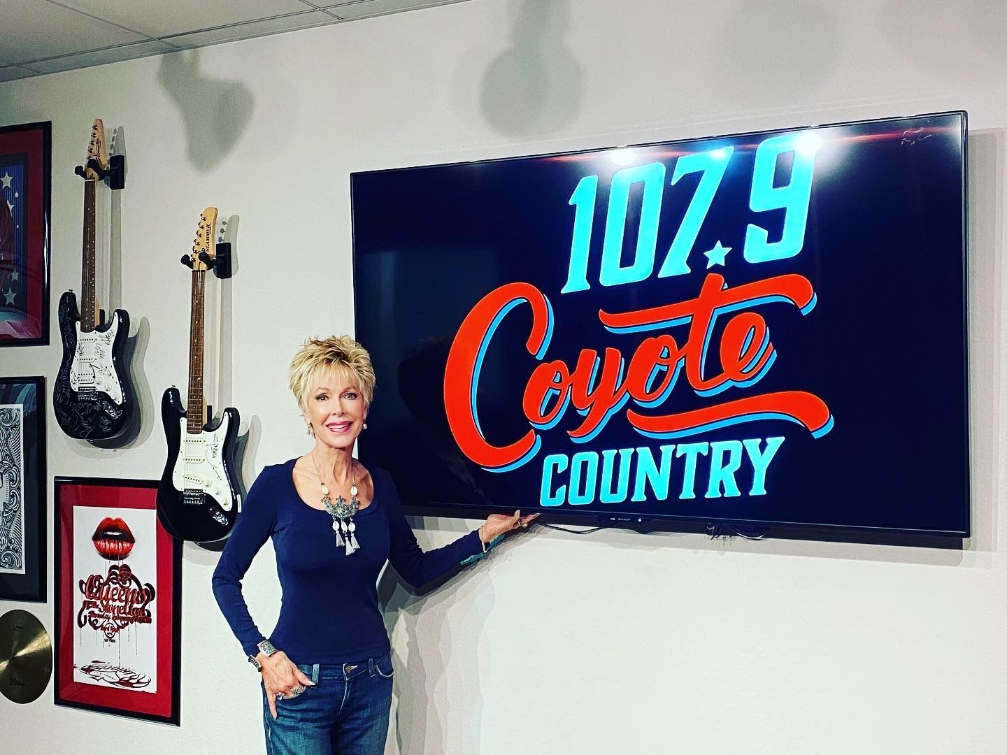 a woman is standing in front of a sign that says 107.9 coyote country