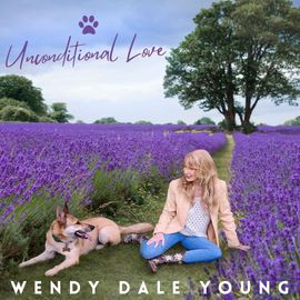 Wendy dale young is sitting in a field of purple flowers with her dog.