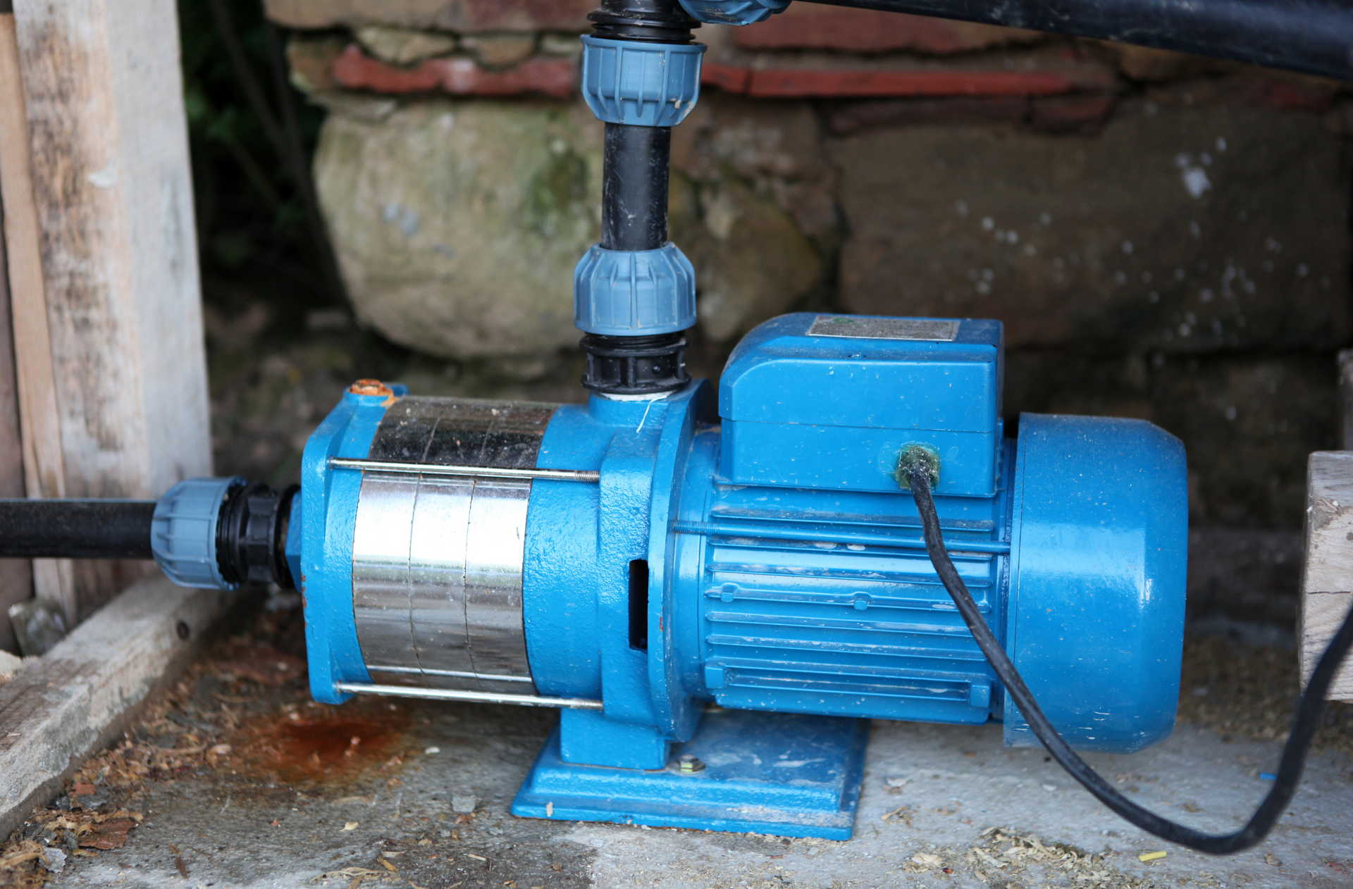 a blue water pump is sitting on the ground next to a pipe