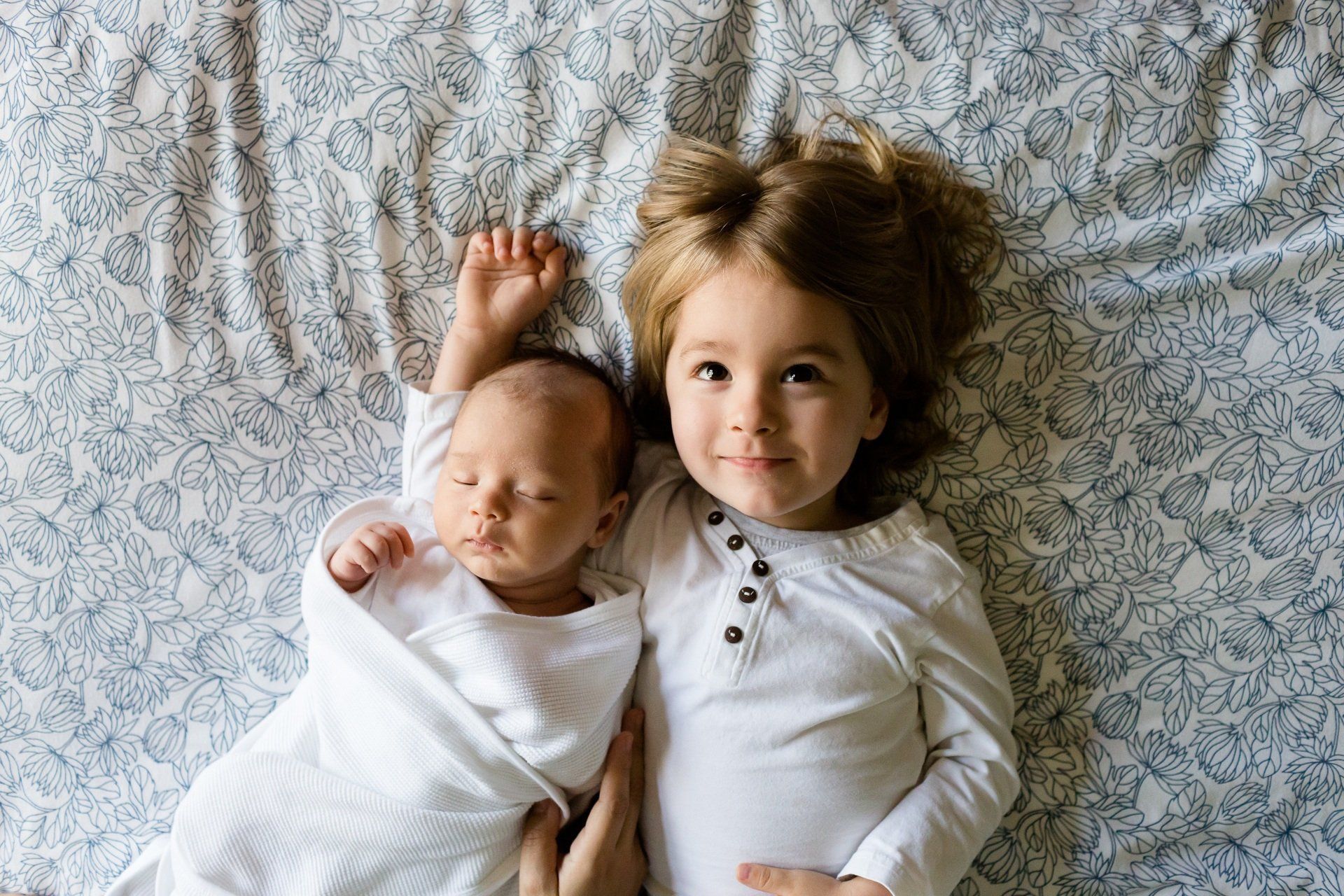 A boy and a baby are laying on a bed.