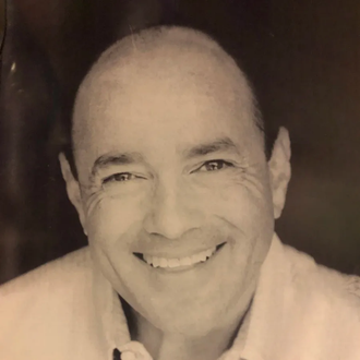 A man with a bald head is smiling in a black and white photo.