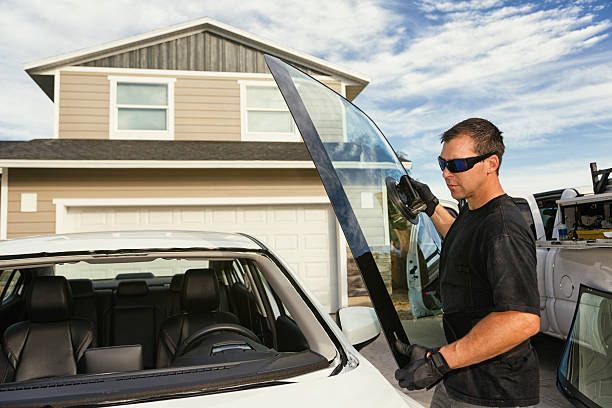 Man installing a new windshield on a white car