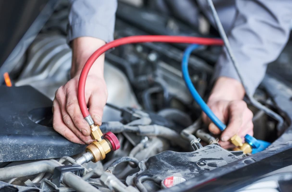 A Person Is Working On A Car With Hose Attached To It — Bartons Auto Air Conditioning In Tolga, QLD