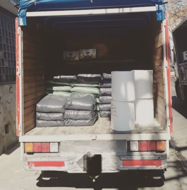 Vista trasera de la caja de un camión cargado con bolsas de material y rollos blancos grandes.