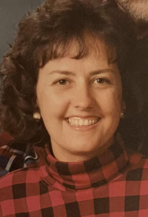 A woman in a plaid shirt is smiling for the camera. Tracy Pellman