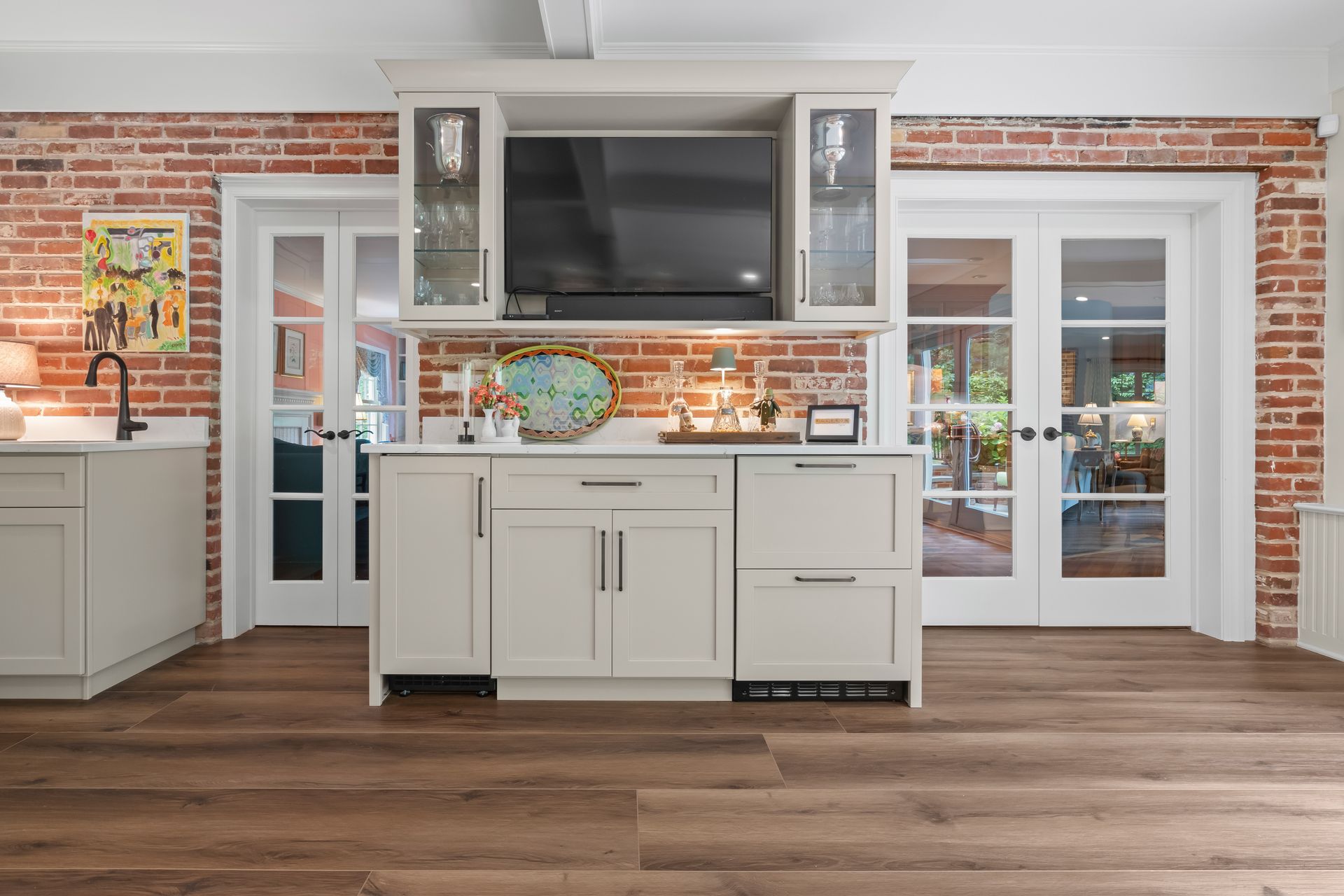 A kitchen with white cabinets and a brick wall.