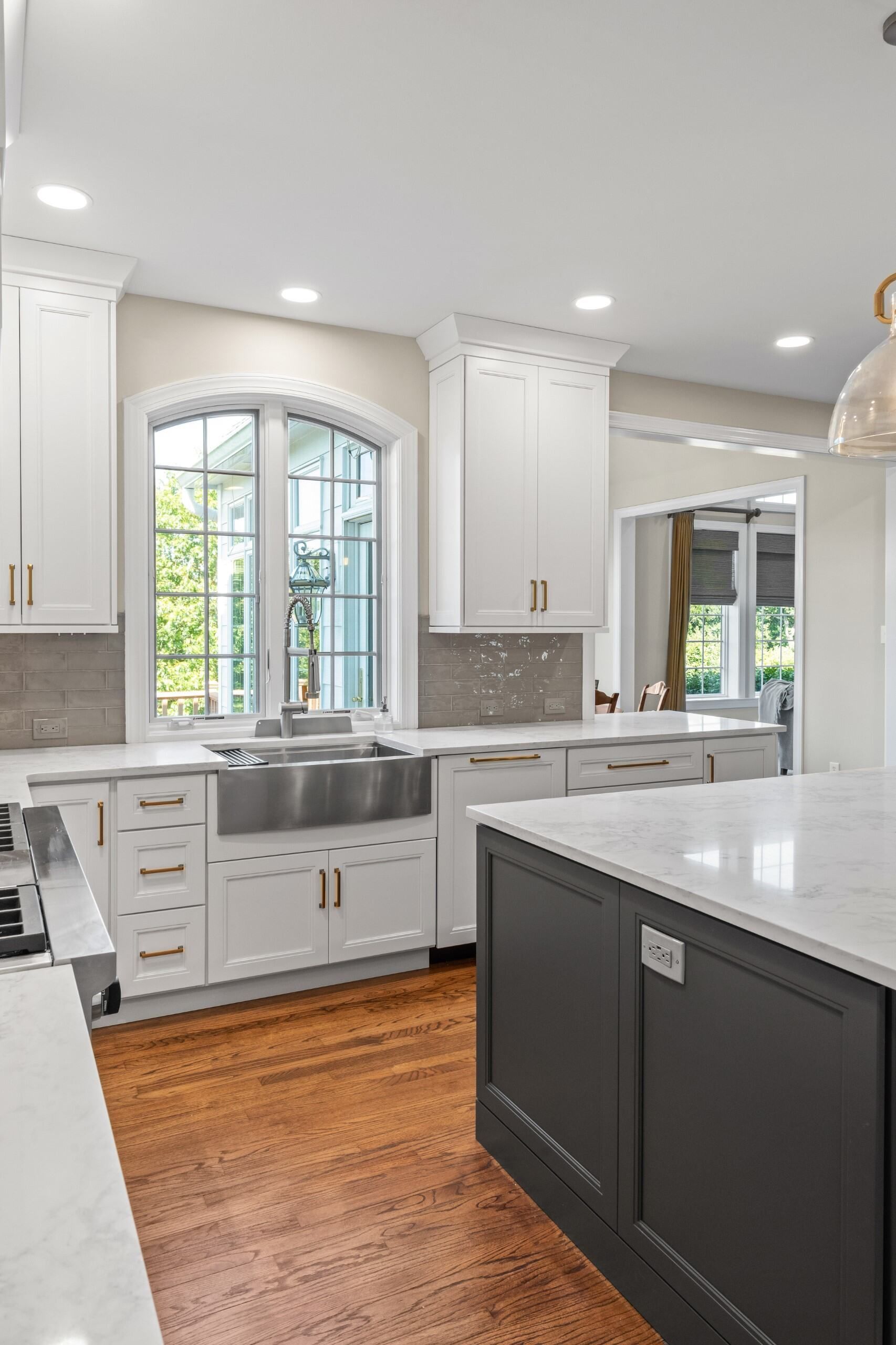 A kitchen with white cabinets , a stainless steel sink , and a large island.