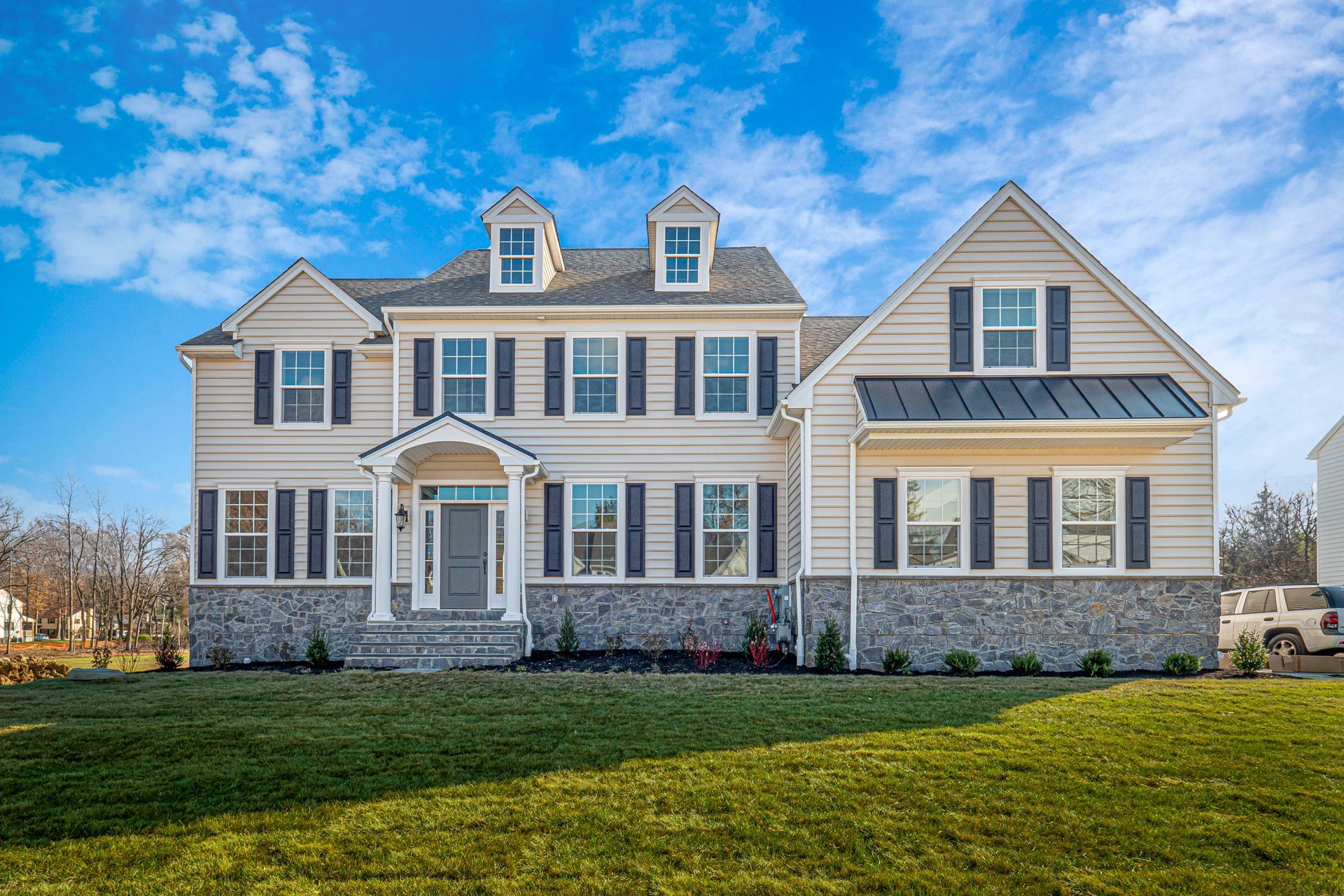 A large white house with black shutters is sitting on top of a lush green lawn.