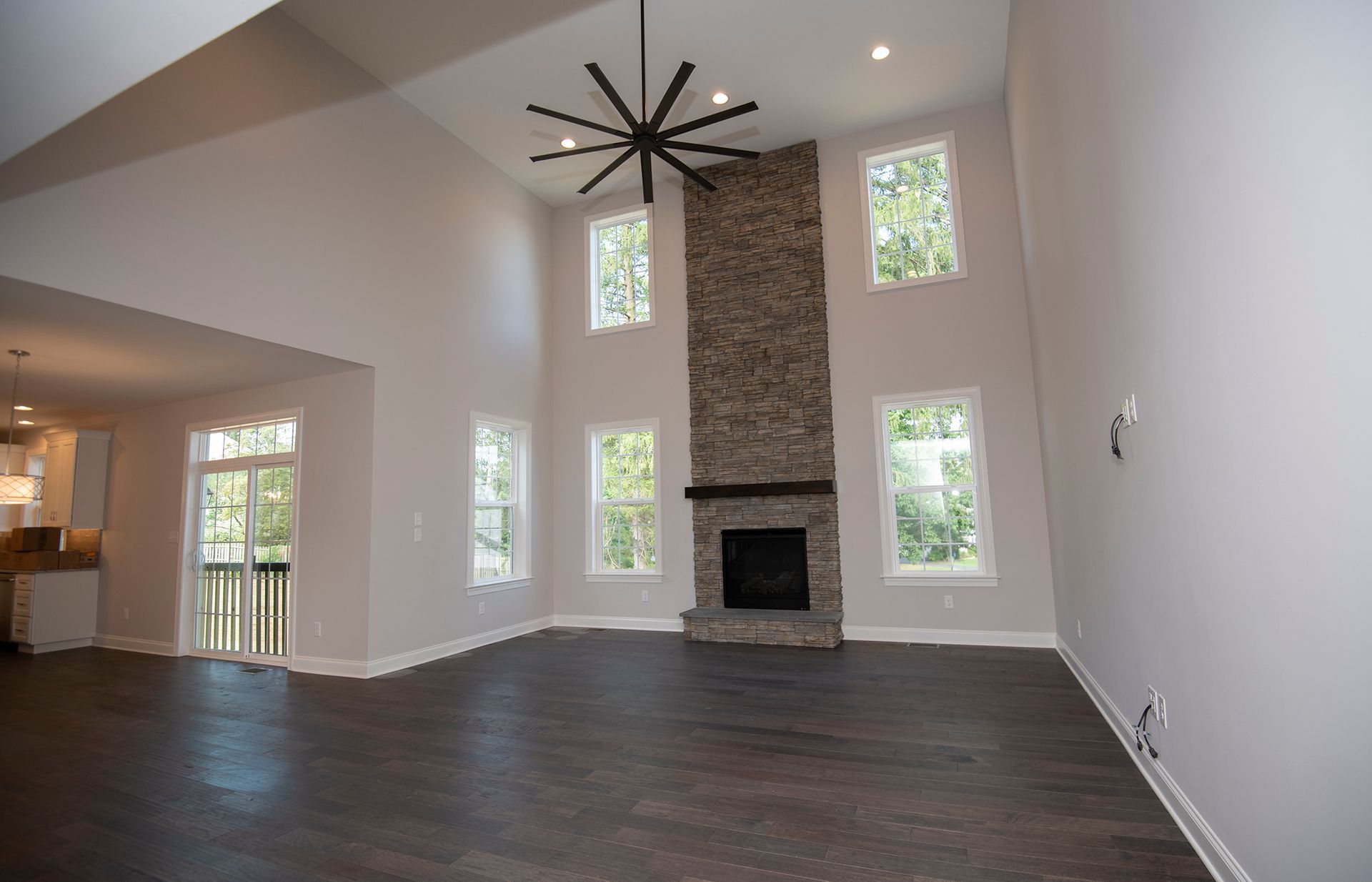 An empty living room with a fireplace and a ceiling fan.