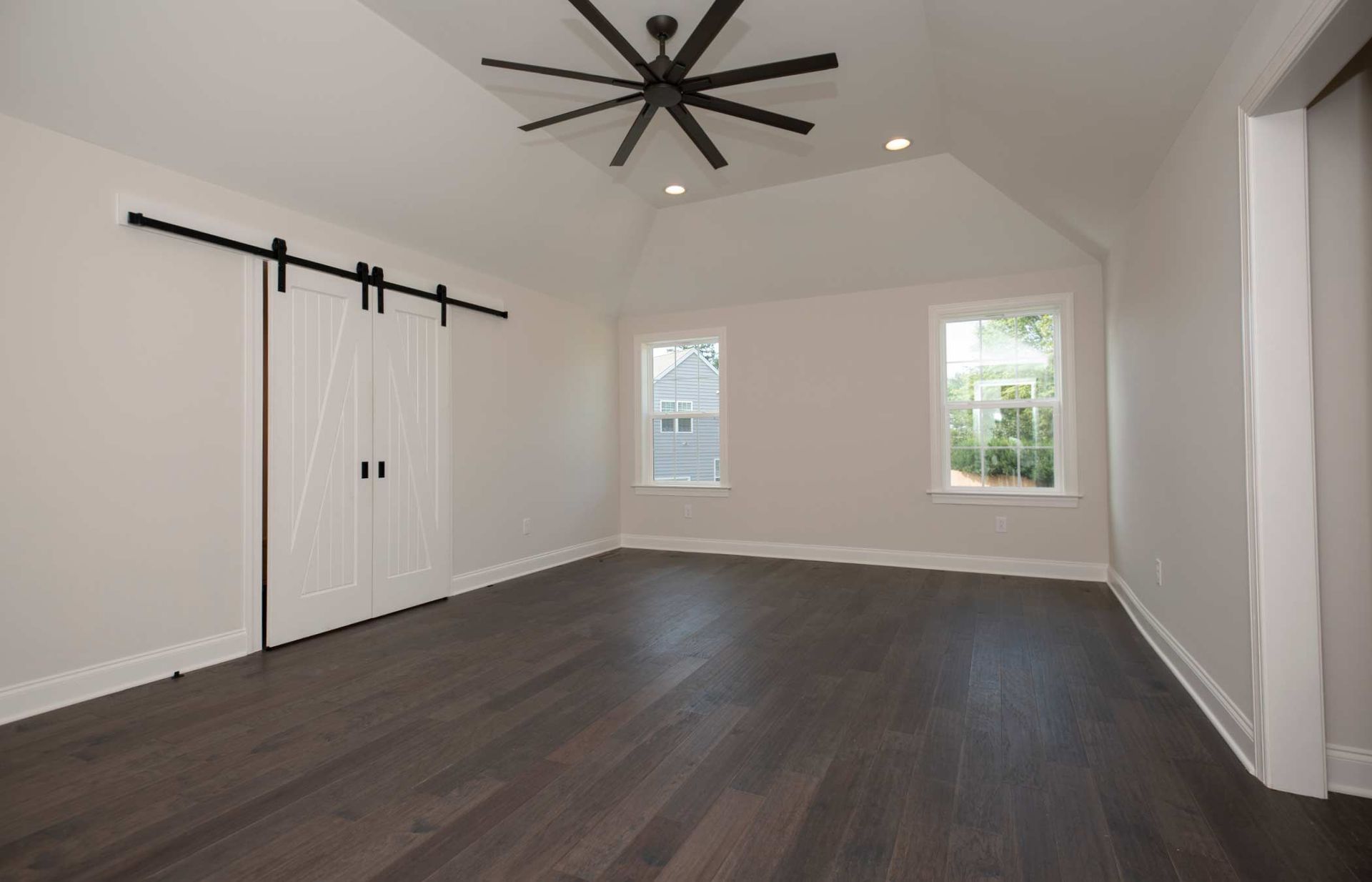 An empty room with sliding barn doors and a ceiling fan